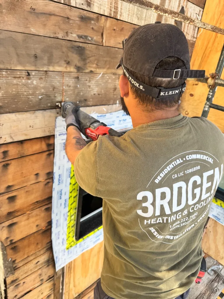 3rdGen technician cutting a wall opening for commercial HVAC infrastructure coordination during an occupied build-out.