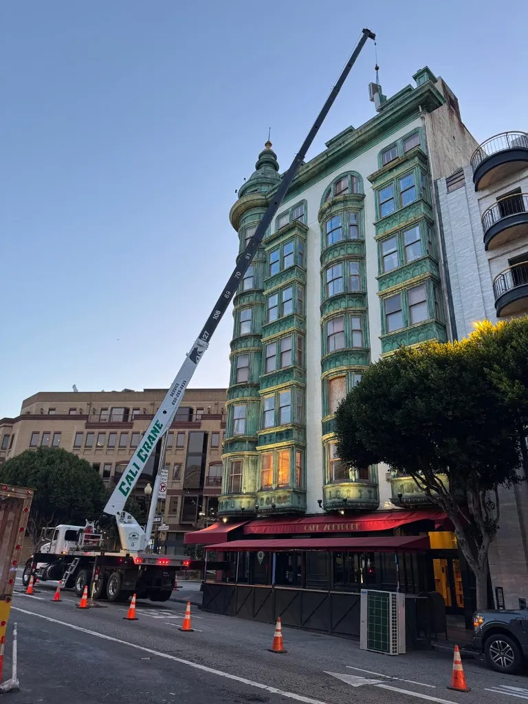 Crane setting commercial HVAC equipment at an occupied San Francisco mixed-use building during modernization by 3RDGEN Building Systems.